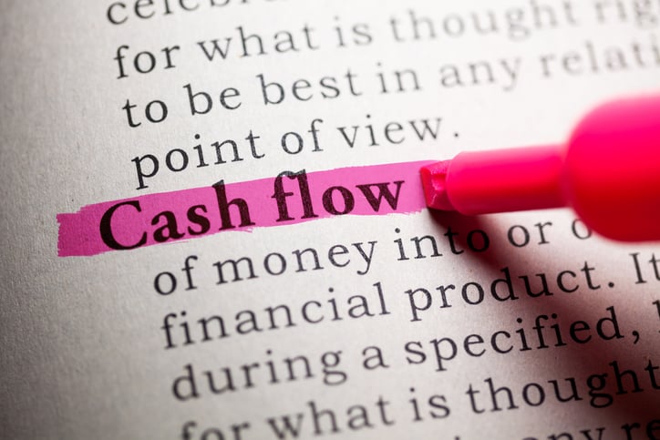 A pink highlighter going over the words cash flow in a textbook.