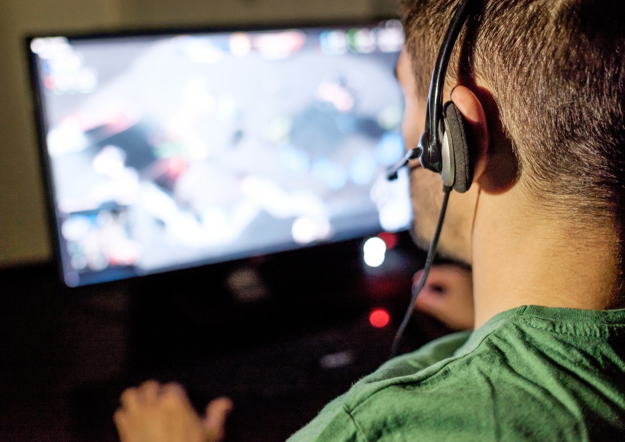 A person wearing a headset playing an online video game on their computer.