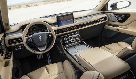 A view of the Lincoln Aviator's dashboard and front seats, showing lush tan leather, clean horizontal lines, and chrome details.