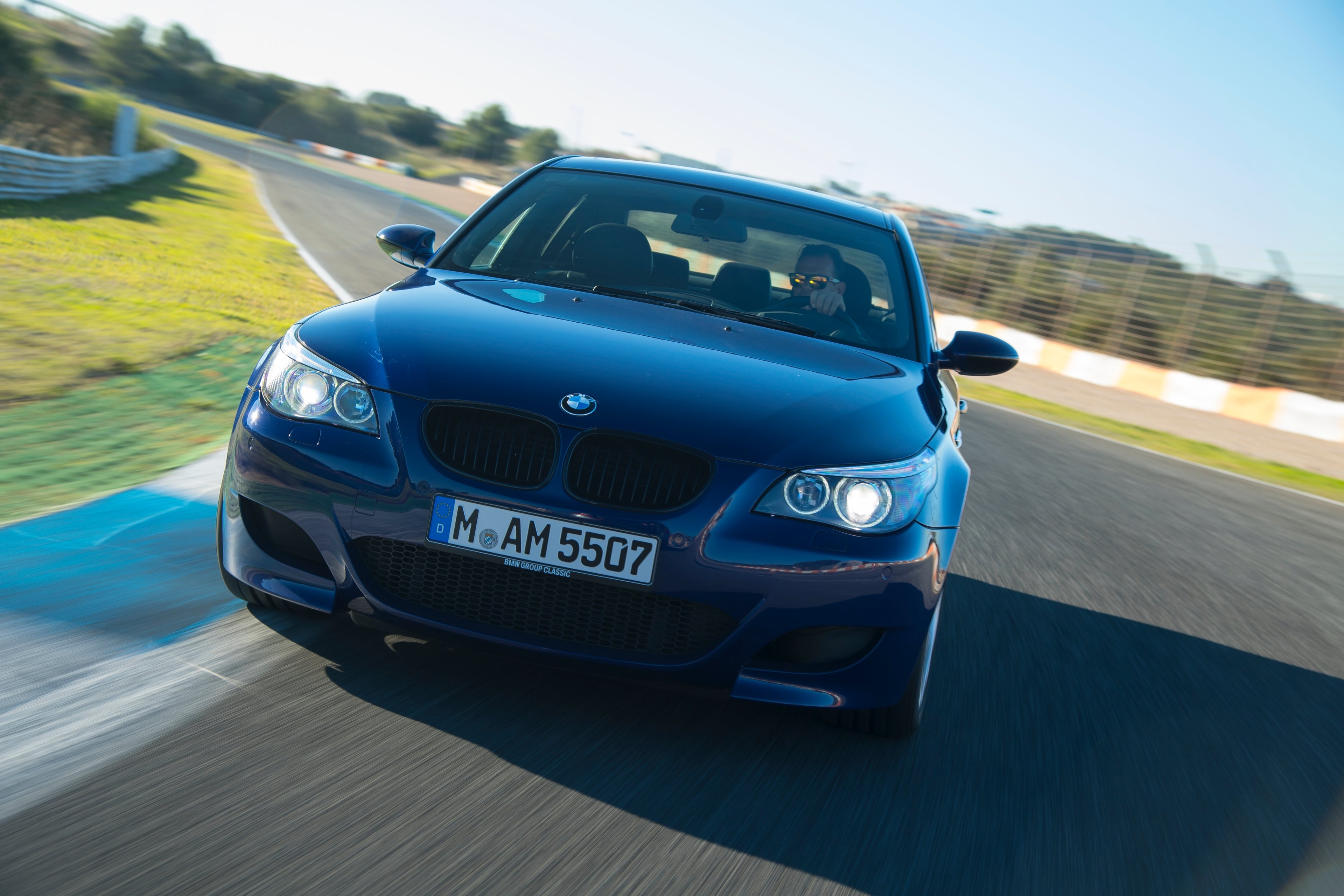 A dark blue BMW M5 on a European testing track.