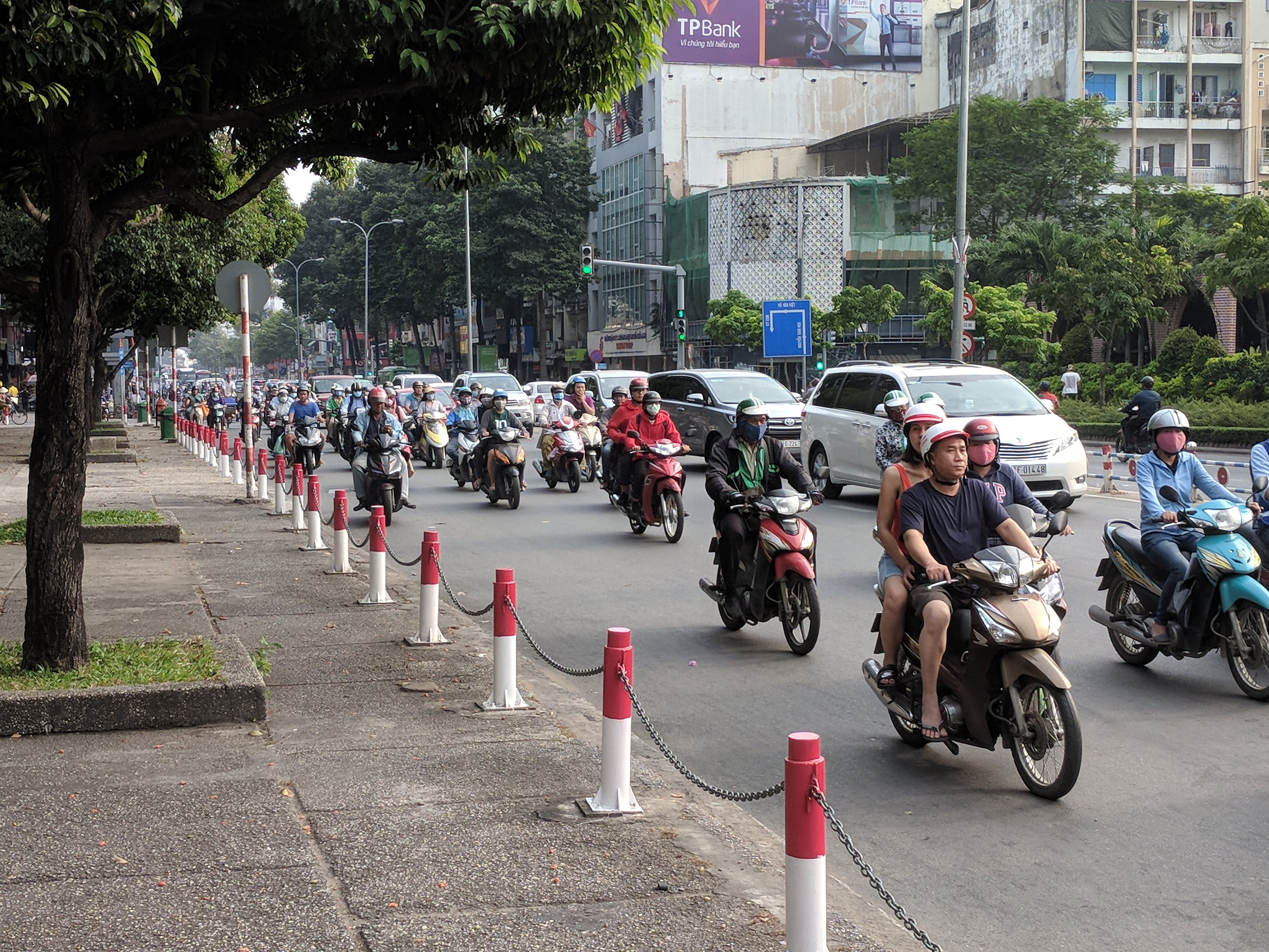 A busy city street in Ho Chi Minh City, Vietnam, filled with motorbikes and a few cars.