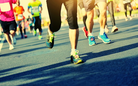 Group of runners on pavement, shoes of different colors, some wearing leggings and some shorts.
