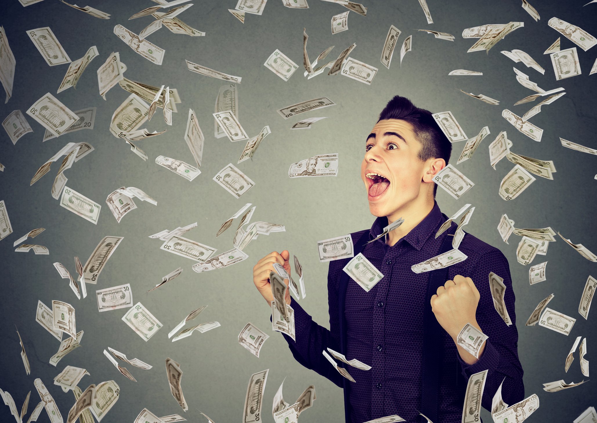 A smiling young man stands in a shower of American paper currency