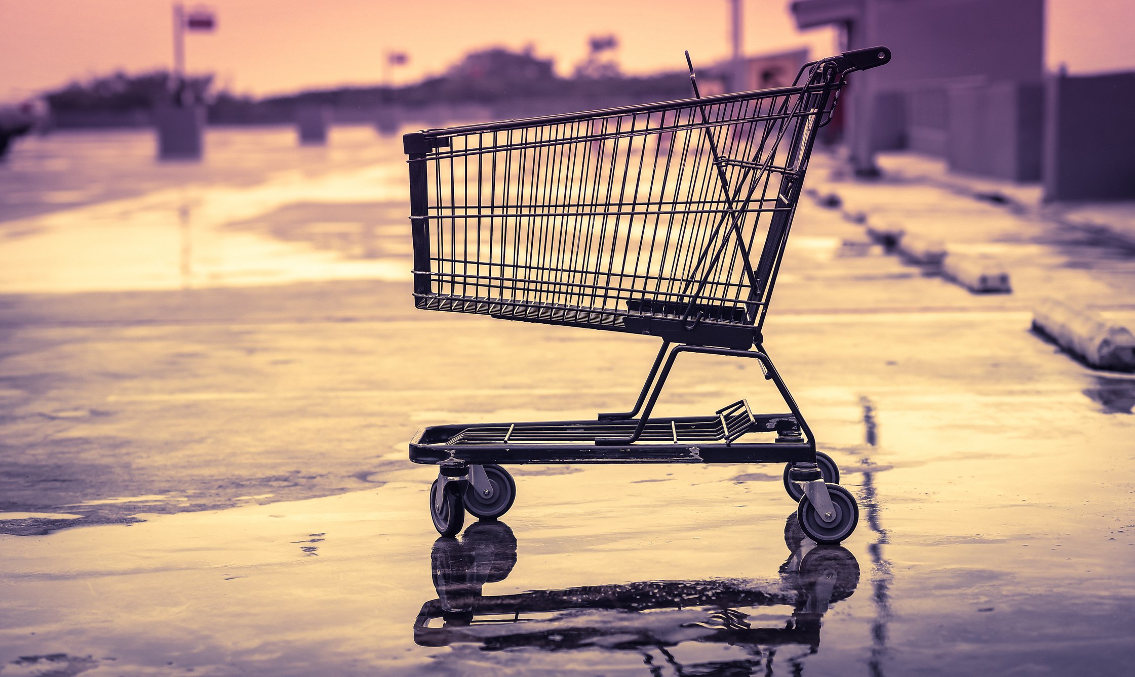 An empty shopping cart in an empty store parking lot