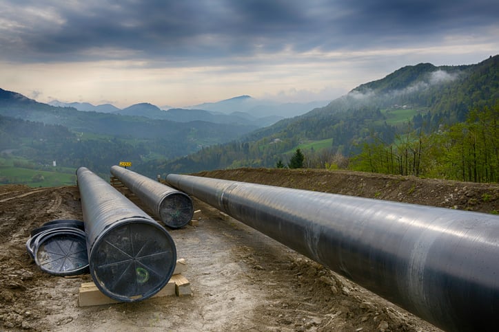 A pipeline under construction with dark clouds on the horizon.