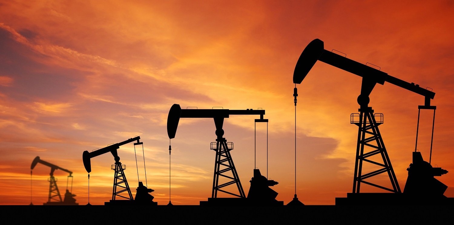 Four oil pumpjacks in operation at sunset
