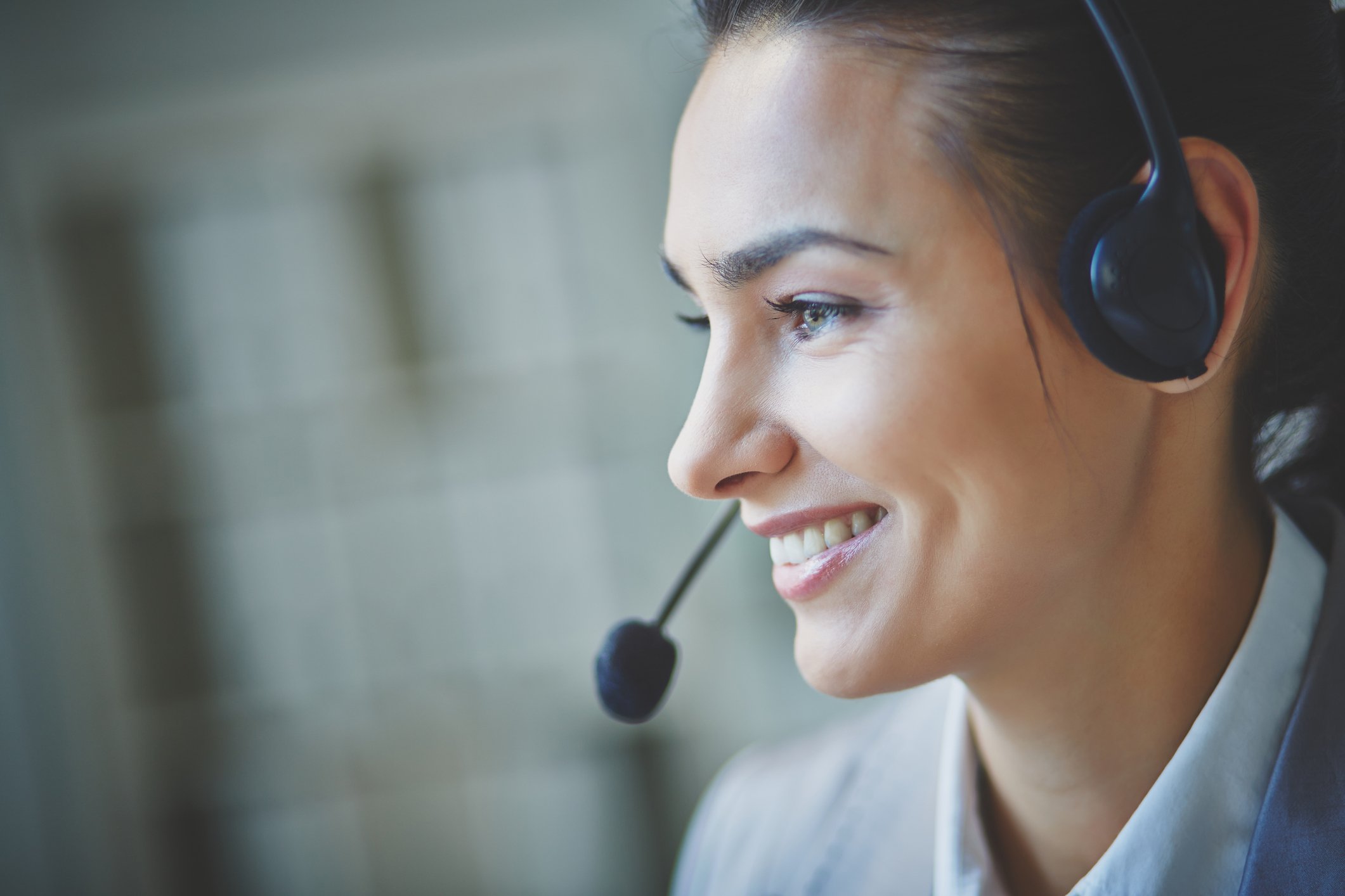 A woman smile while wearing a headset.