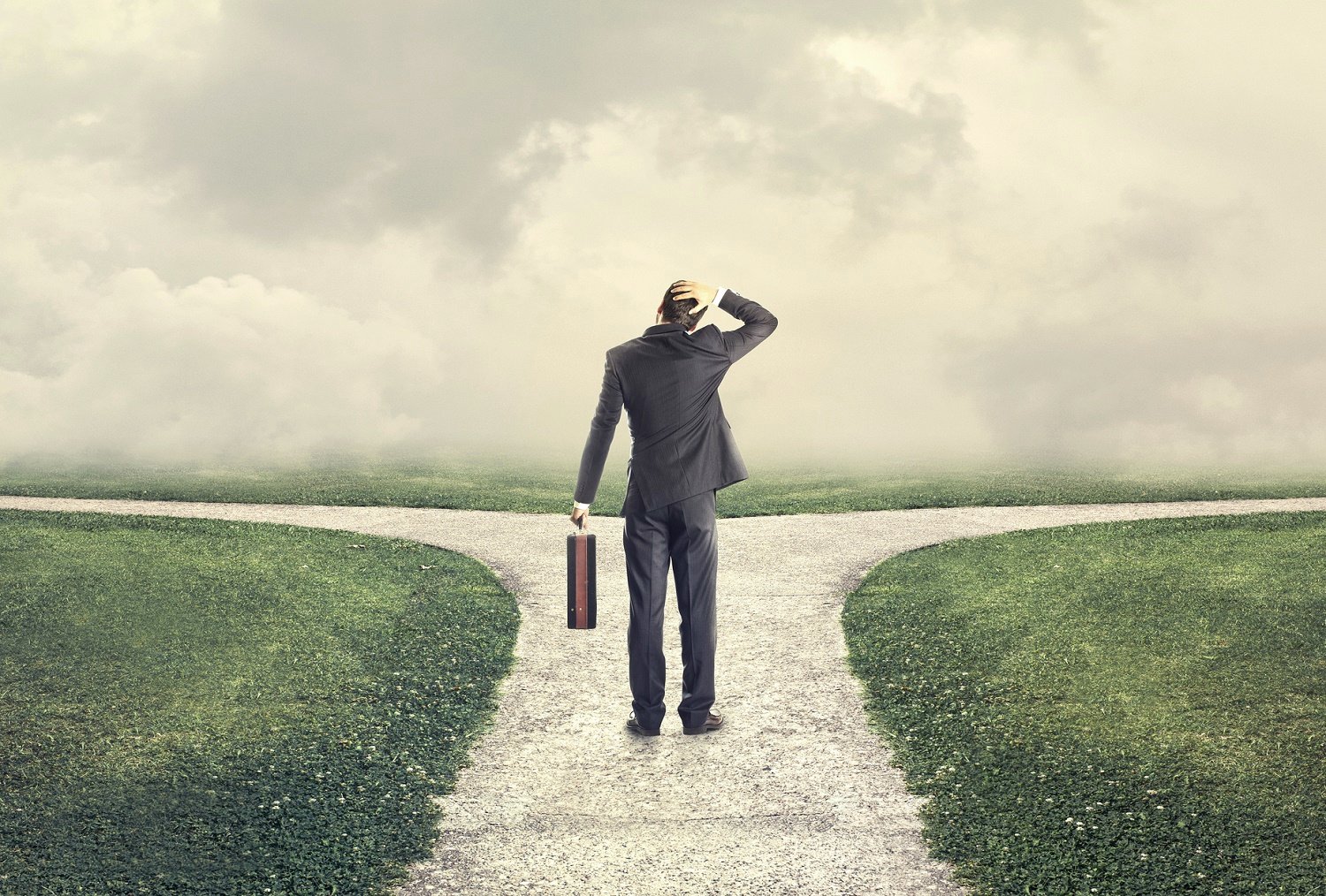 Businessman with briefcase standing at a crossroads.