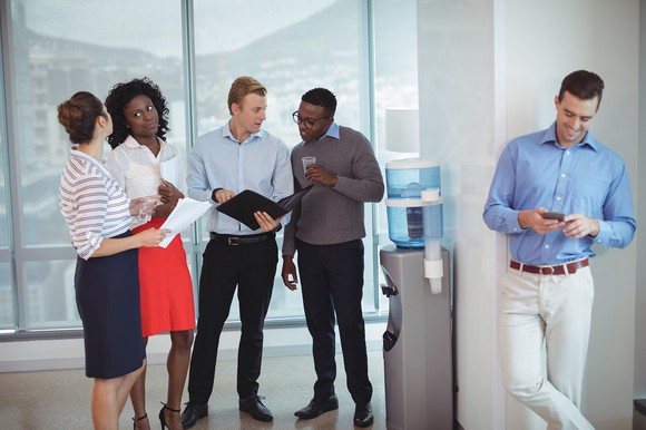A group of colleagues standing around a water cooler. 