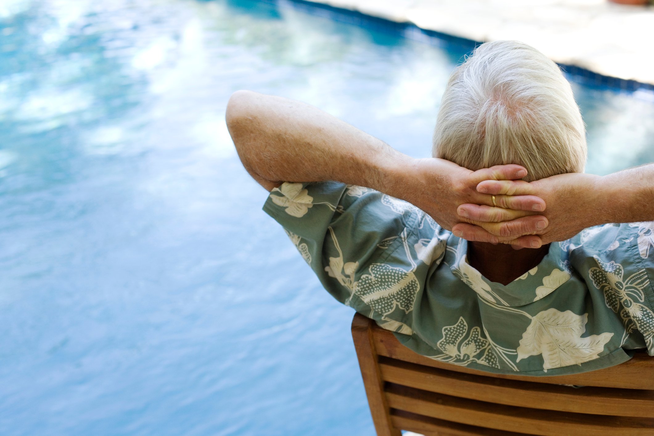 A senior citizen relaxes by the pool.