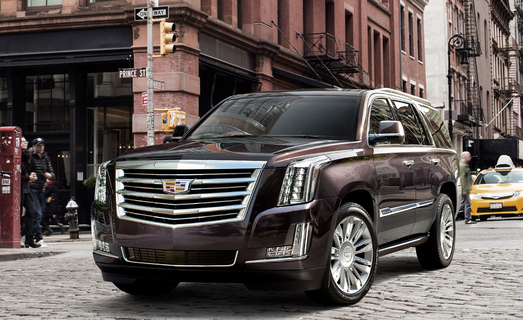 A dark brown Cadillac Escalade, a large luxury SUV, on a New York City street.