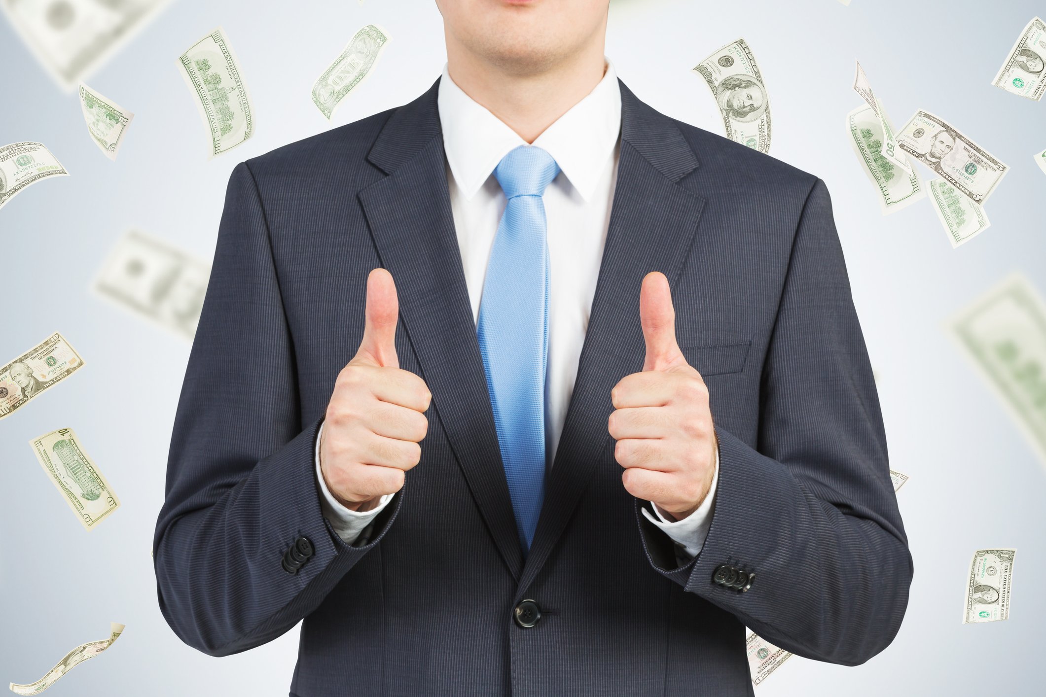 Businessman giving two thumbs up with money falling all around him.