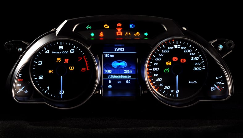 A dashboard instrument cluster, with a tachometer, speedometer, and other indicators visible