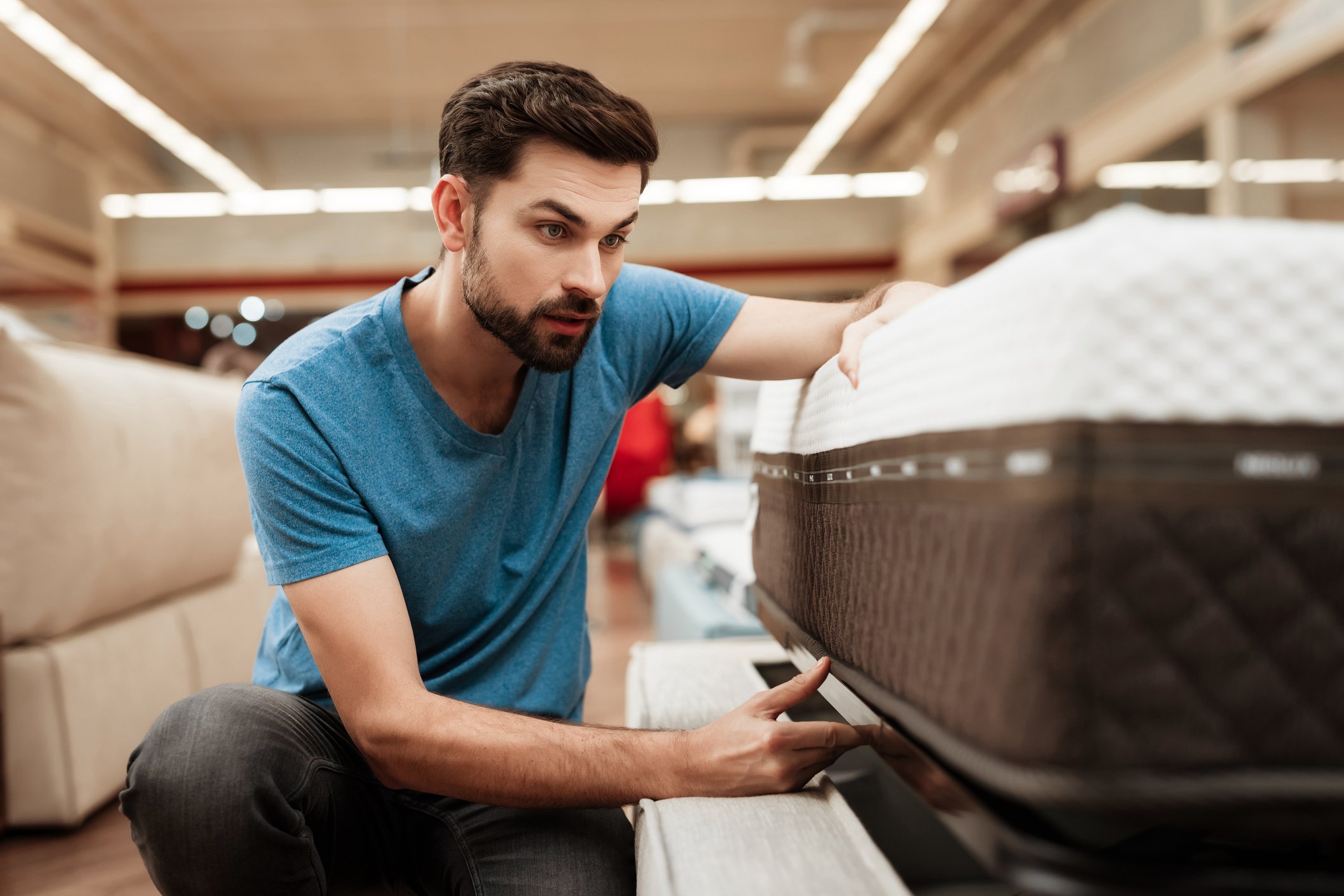 Man looking at mattress tag in furniture store.