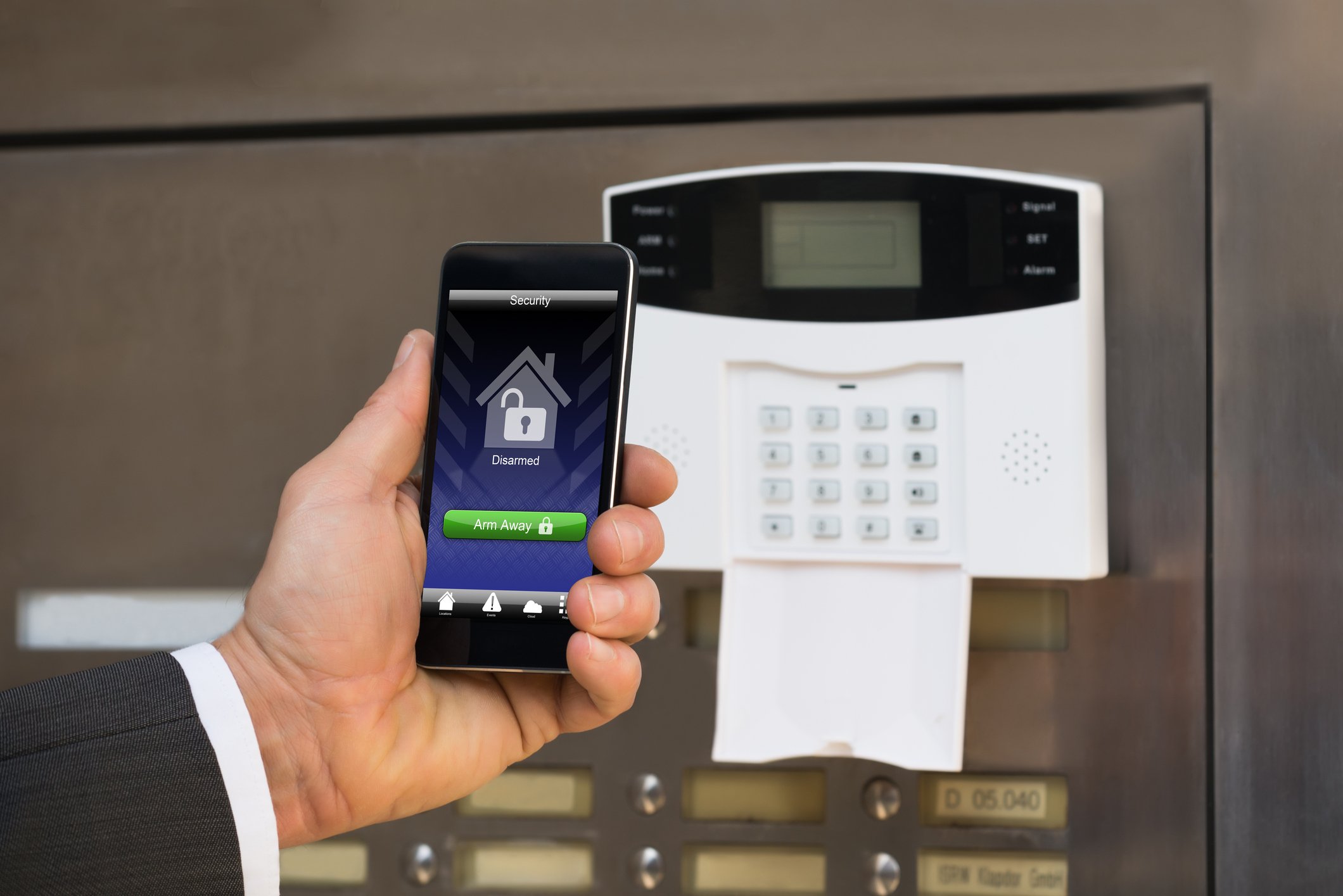 Home alarm keypad and cellphone showing unlock icon