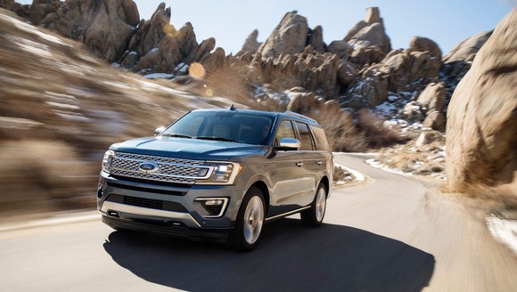 Ford's Expedition SUV driving on narrow path in between rocky terrain.