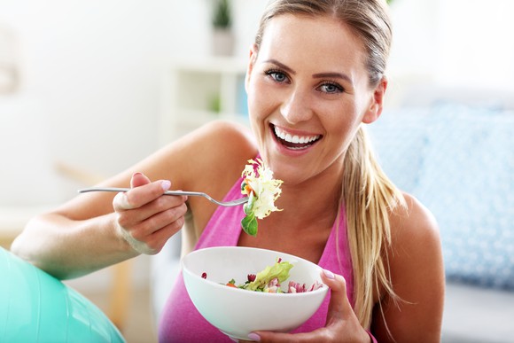 A young woman eats a salad.
