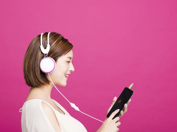 A young woman listens to music on her phone.