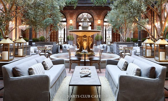 An atrium with foliage, gray couches, and other neutral-colored furniture surrounding a water fountain