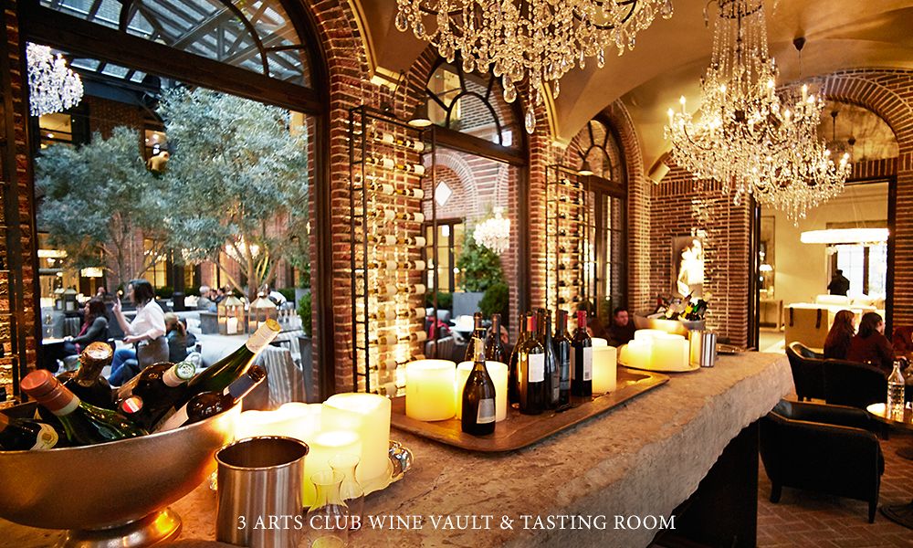 A wine bar in a dimly lit room with fancy chandeliers hanging from the ceiling