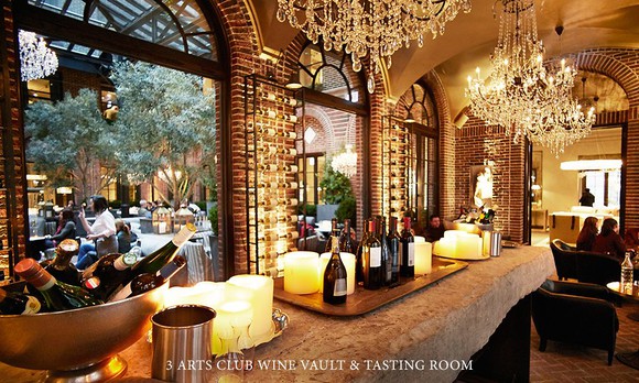 A wine bar in a dimly lit room with fancy chandeliers hanging from the ceiling