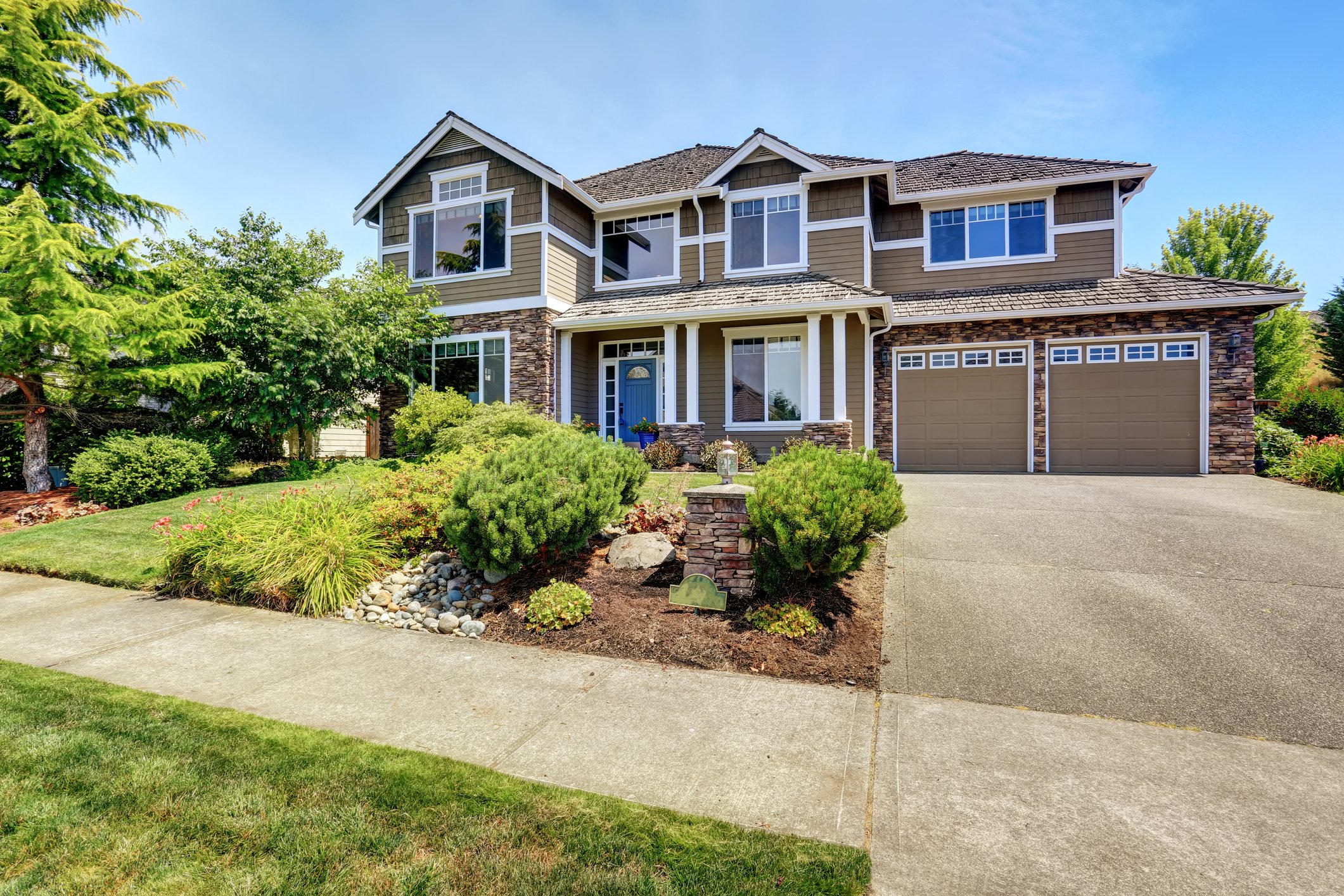 A light brown house with a nice front yard and two-car garage