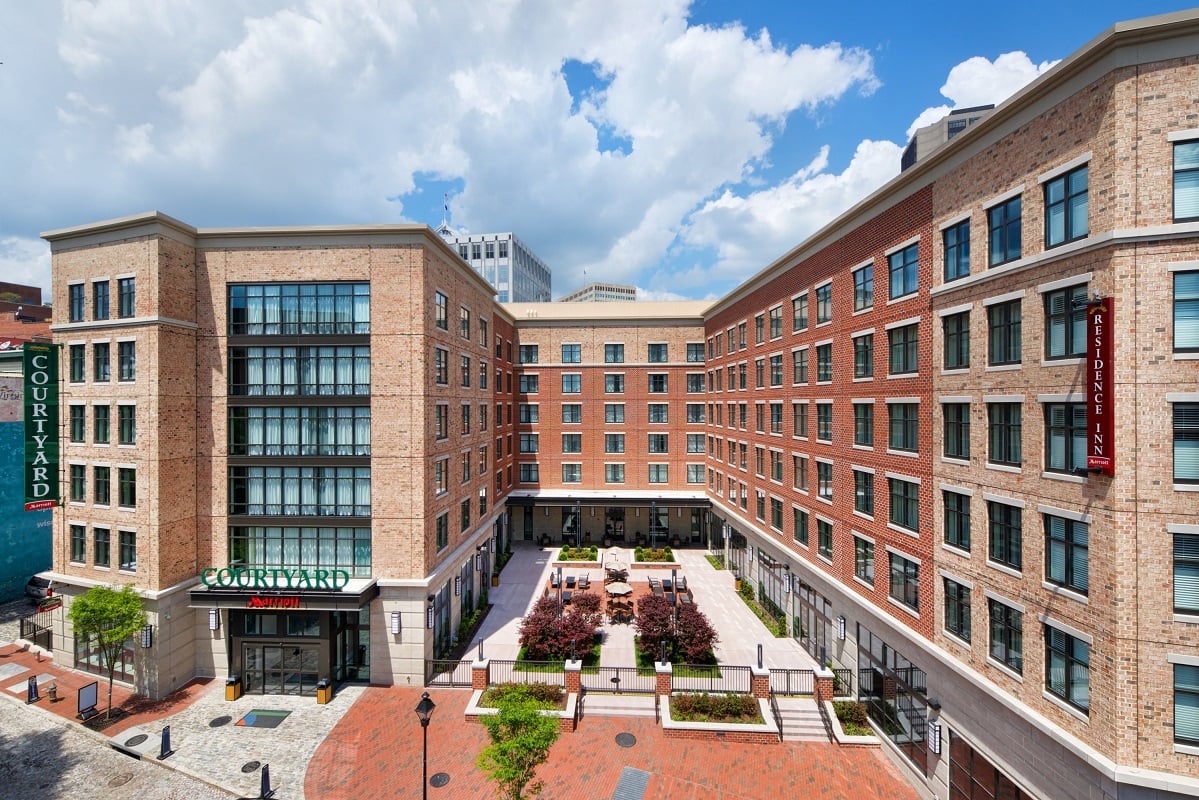 Hotel and courtyard in six-story building on a partly cloudy day.