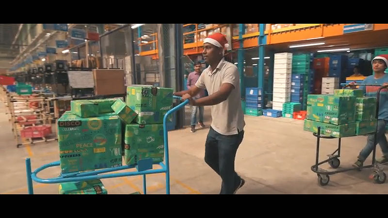 A Flipkart warehouse worker moves a cart of merchandise.