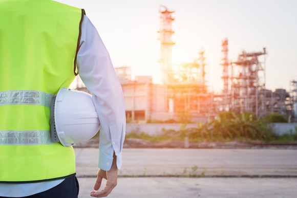Construction worker holding hard hat looking at energy infrastructure.