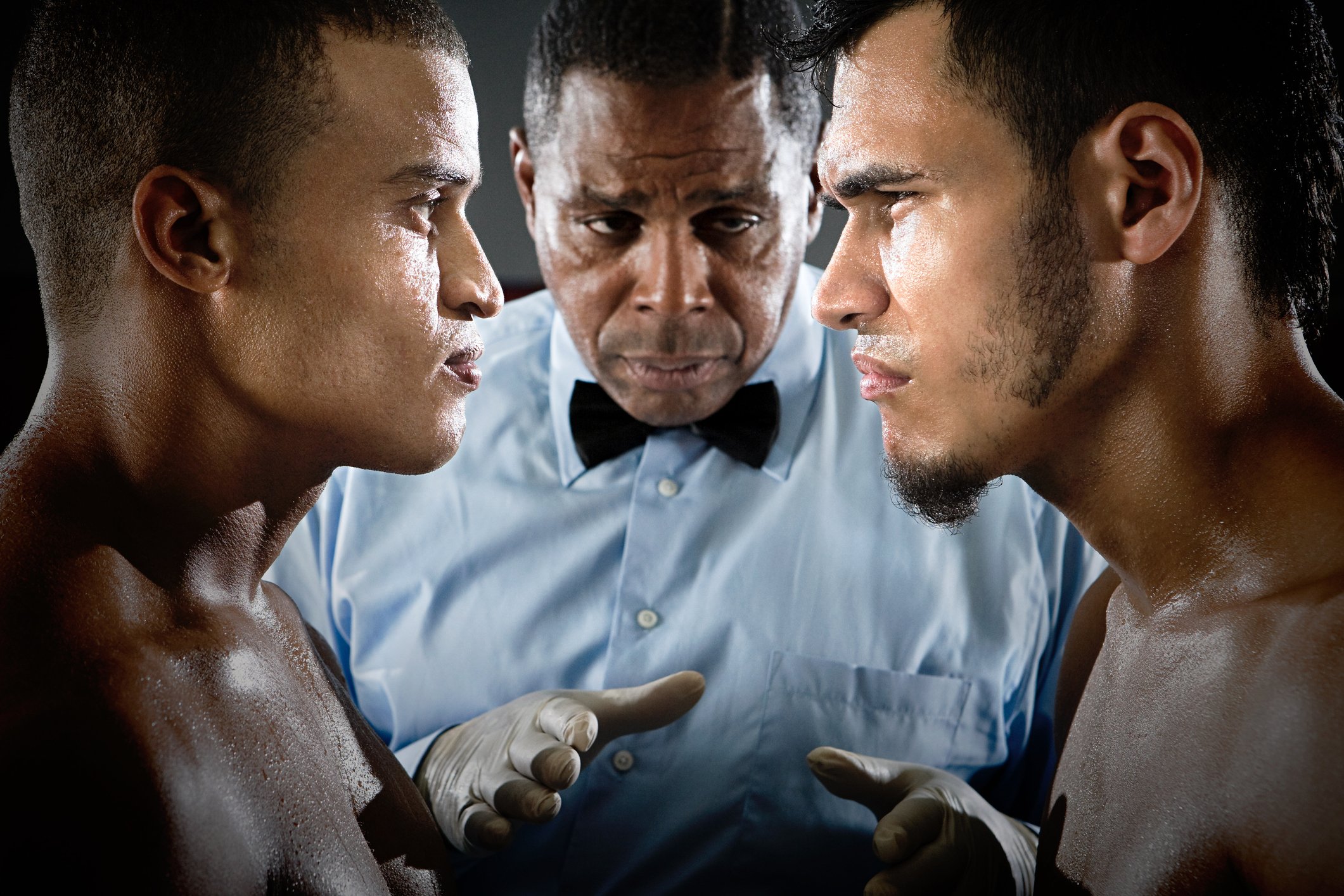 Two boxers face to face and a referee.