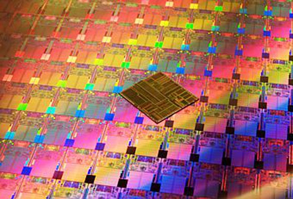 A wafer of Intel processors with a chip on top of the wafer.