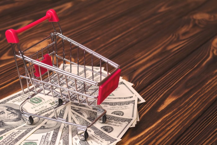 A shopping cart with cash underneath.