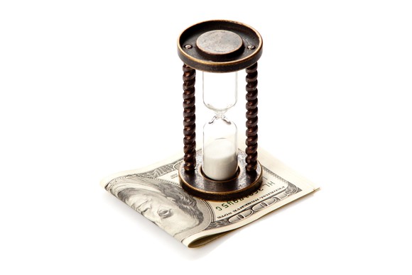 Sand clock on pile of money