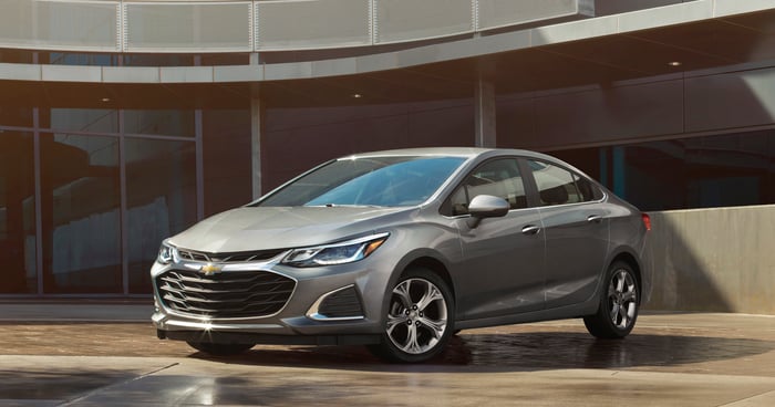 A silver 2019 Chevrolet Cruze, a compact sedan, parked outside an office building.