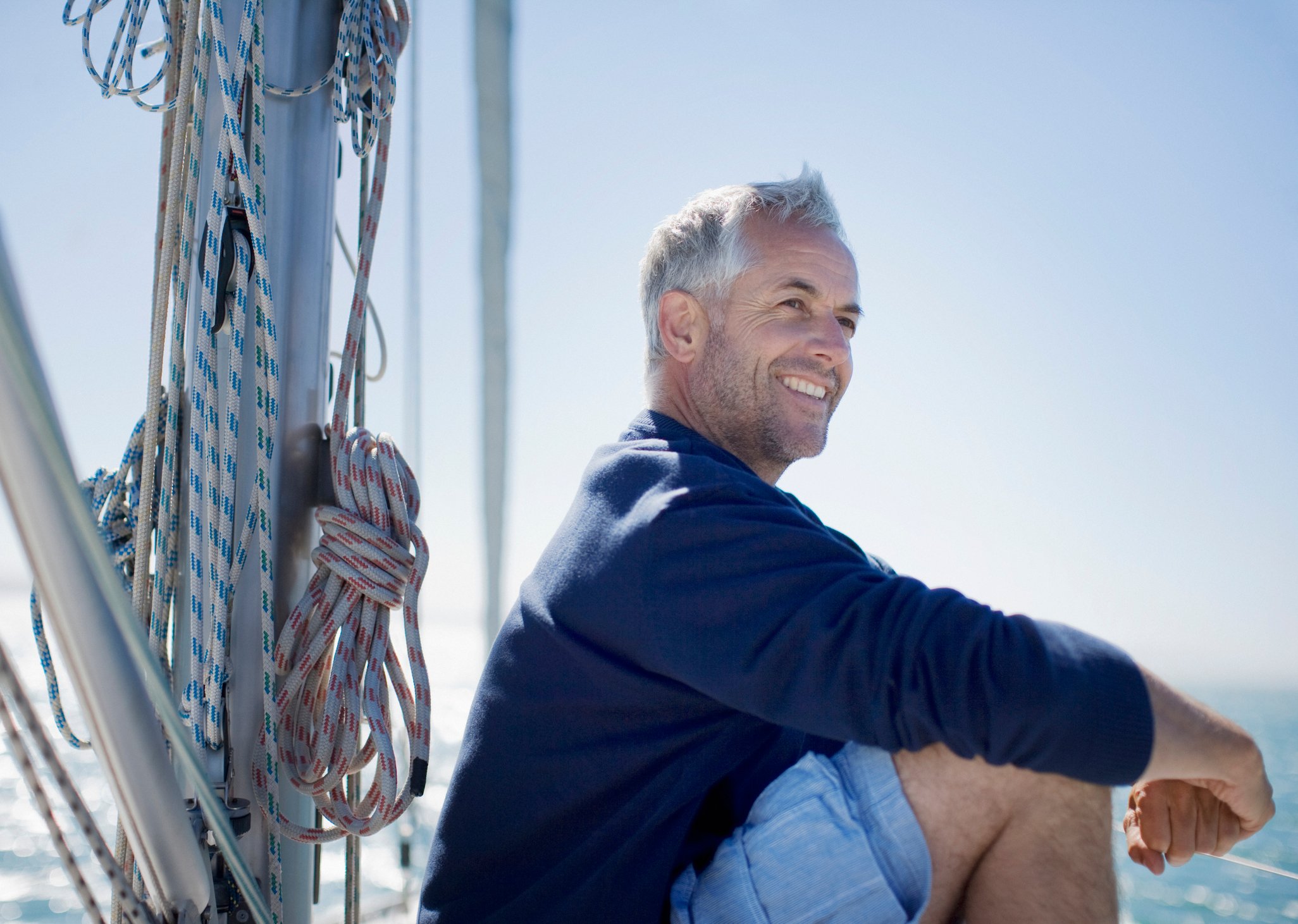 Older man out on a boat smiling.