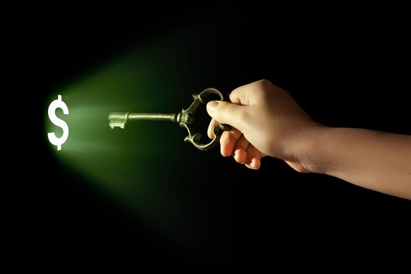 A person moving a key towards a dollar sign.