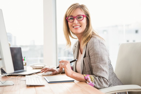 Middle-aged woman wearing glasses and a blazer sitting at an office desk