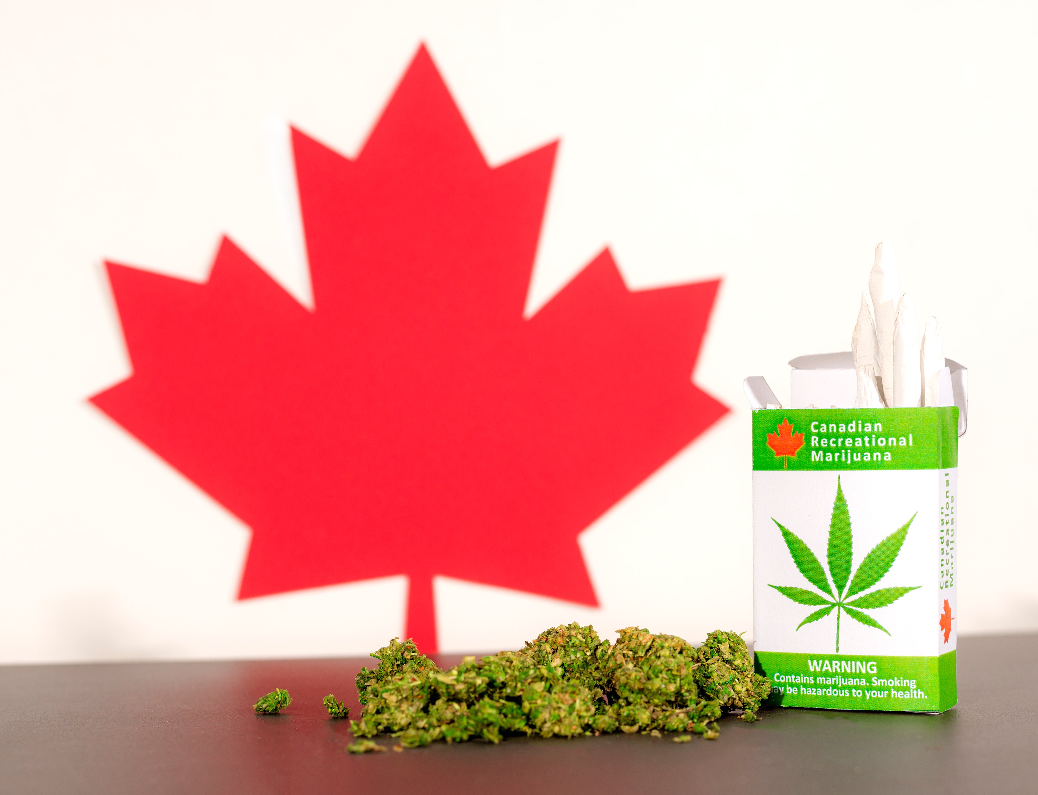 Canadian red maple leaf image next to marijuana buds and a pack of cannabis cigarettes