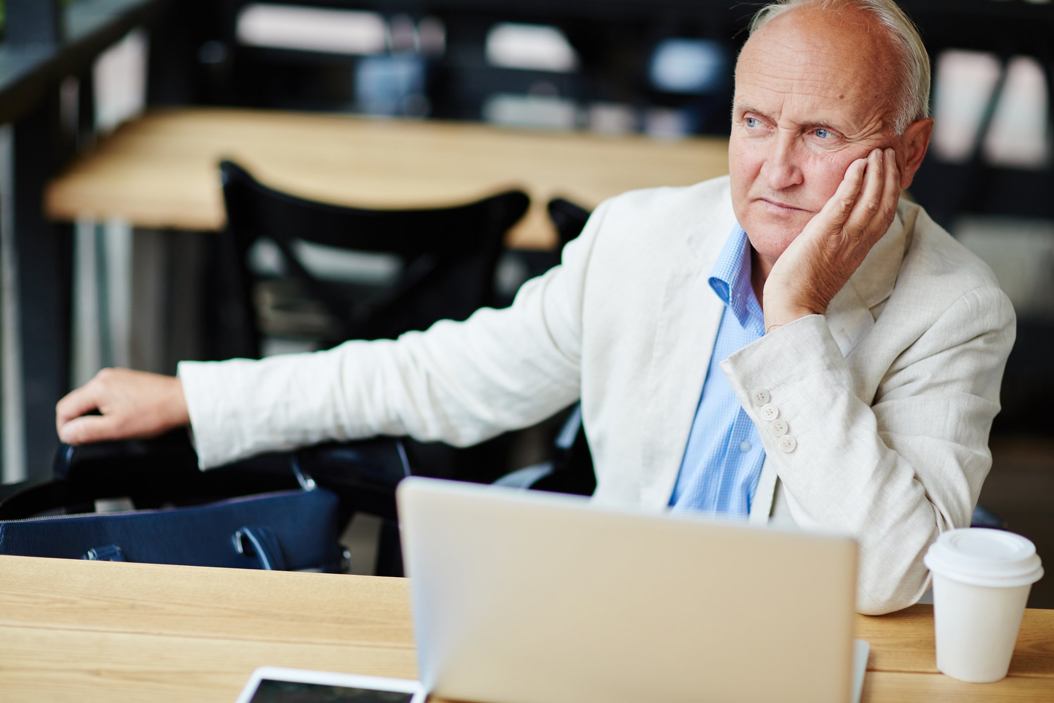 Older man sitting at table thinking.