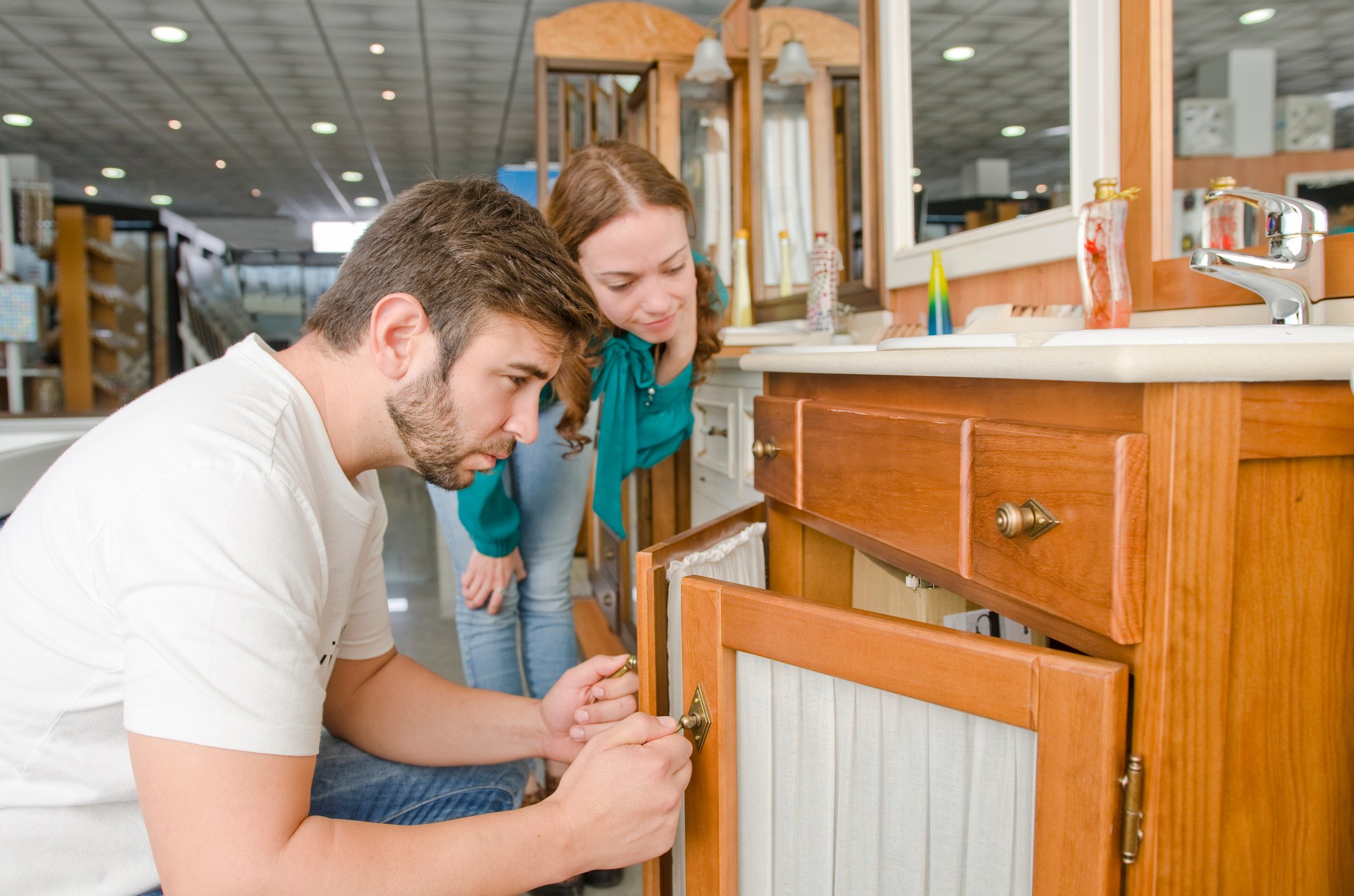 A couple examining a bathroom sink cabinet at a store