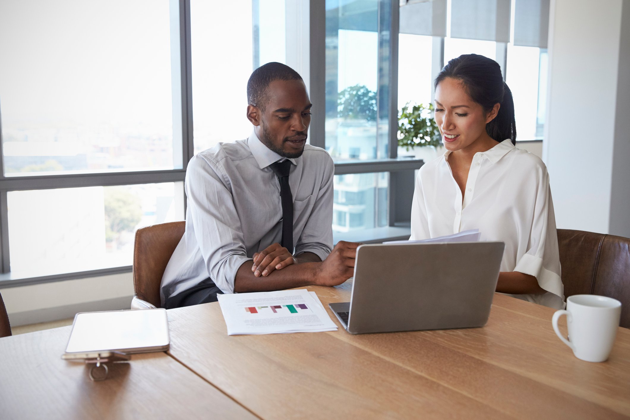 Professionally dressed man and woman looking at a laptop