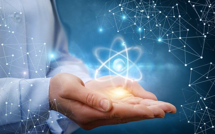 A woman cupping her hands with a giant atom hovering above her palms