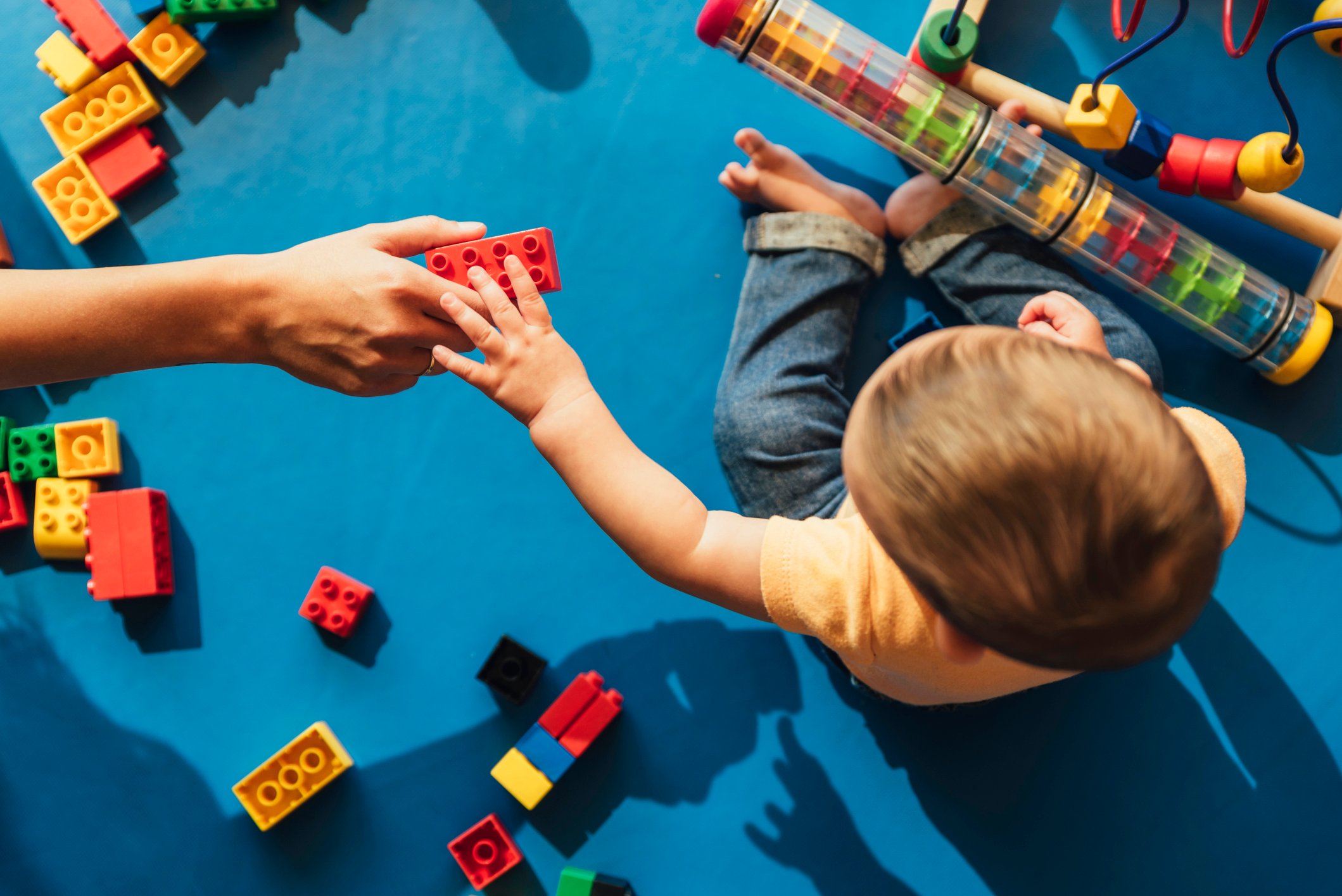 A young child is handed a connectiong block toy.