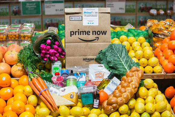 An Amazon-branded grocery bag sits atop a pile of fruits and other popular items found at Whole Foods