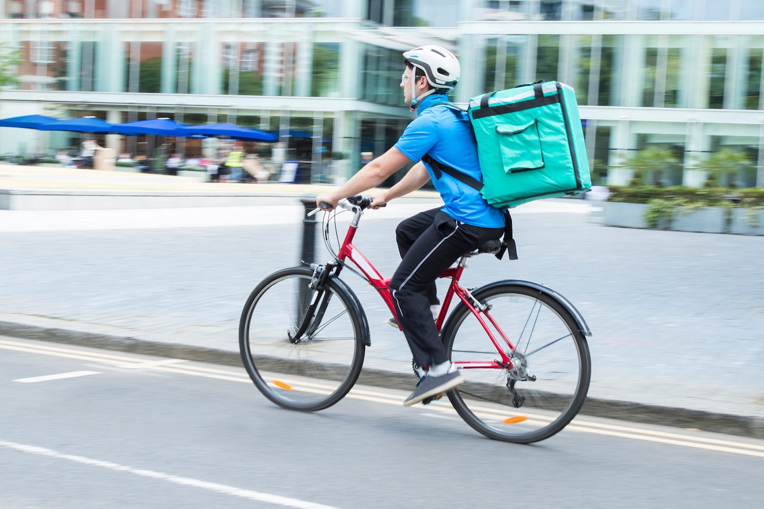 Man riding on bike with food delivery bag on his back.