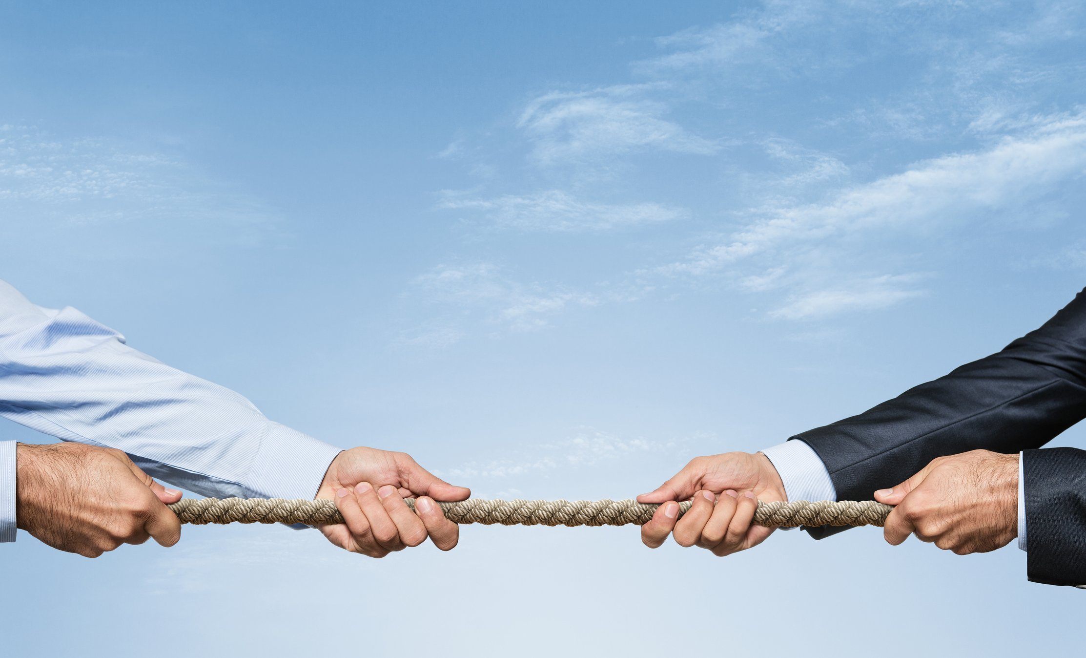 Two businessmen in tug of war with rope