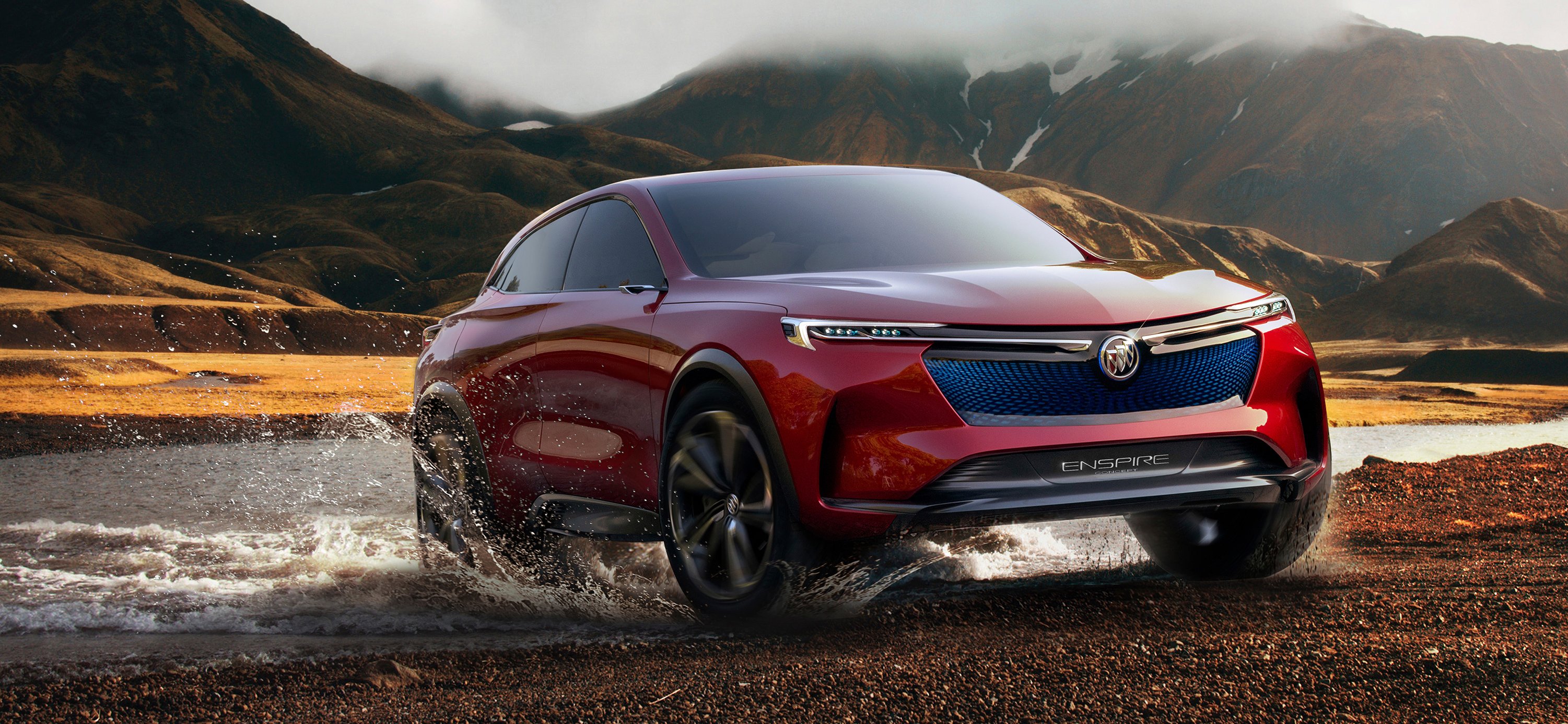 The red Buick Enspire concept is shown in rugged mountainous surroundings, appearing to have just emerged from a stream.