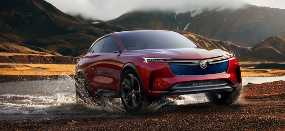 The red Buick Enspire concept is shown in rugged mountainous surroundings, appearing to have just emerged from a stream.