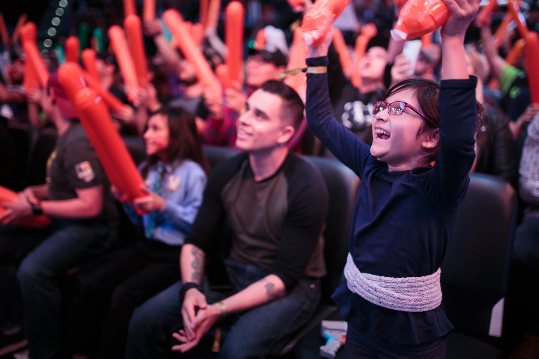 A child cheering among a crowd fans at Overwatch League event at Blizzard Arena.