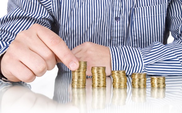 Man stacking coins in piles that grow.